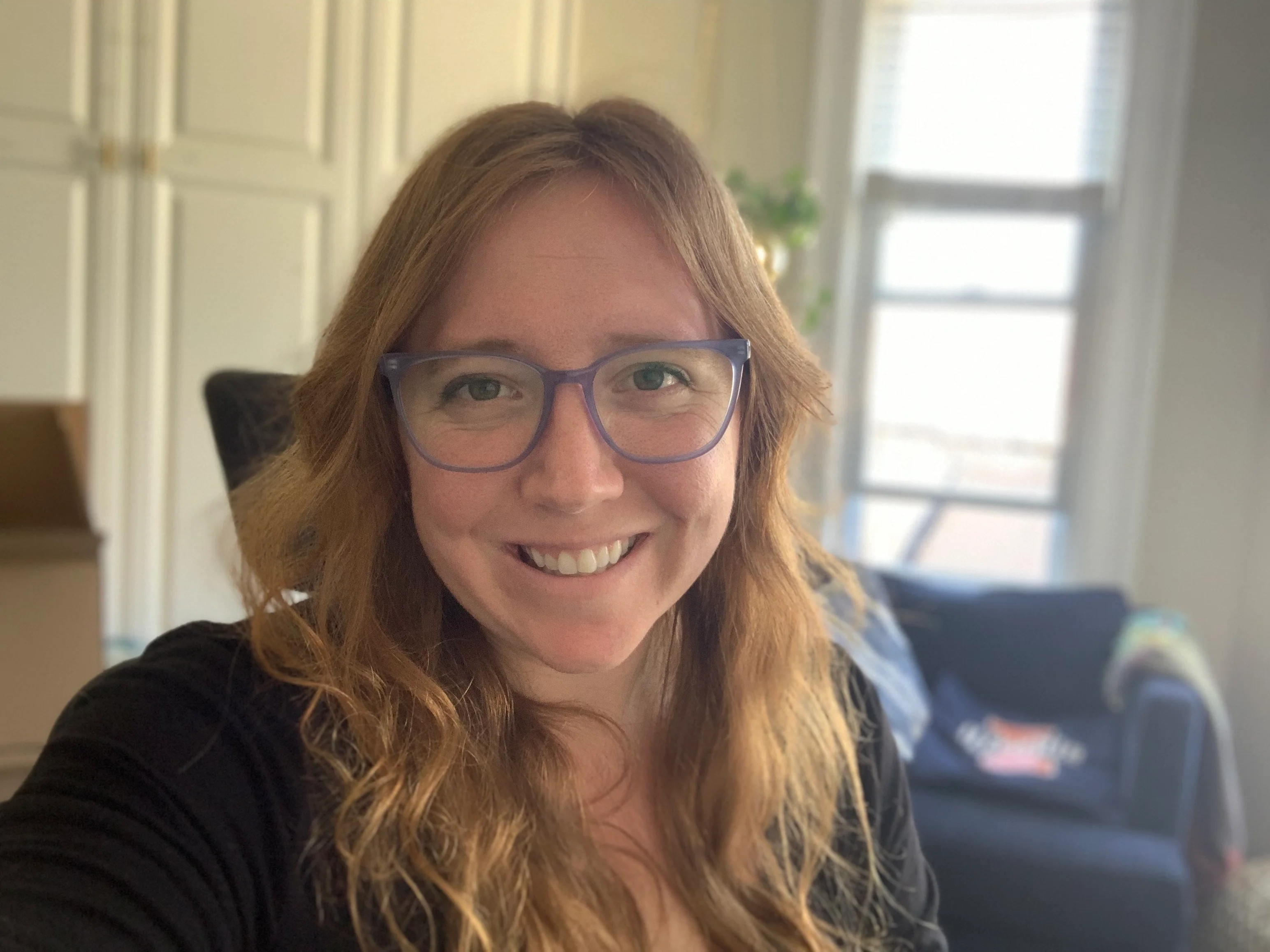 Woman with glasses smiling and looking directly at the camera