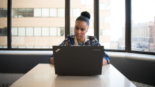 Woman using laptop concentrating Business woman on laptop sitting in front of window