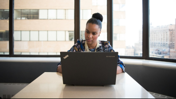 Woman using laptop concentrating Business woman on laptop sitting in front of window